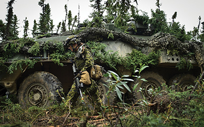 Soldier in front of a Coyote armoured vehicle.