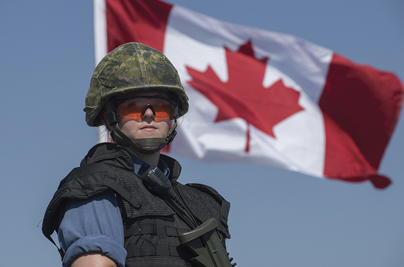 Femme matelot devant le drapeau canadien.