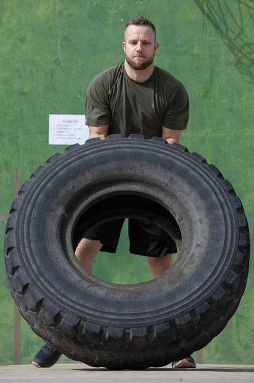 Un militaire sentranant avec un pneu.