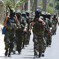 Armed hooded Hamas militants marching in streets.