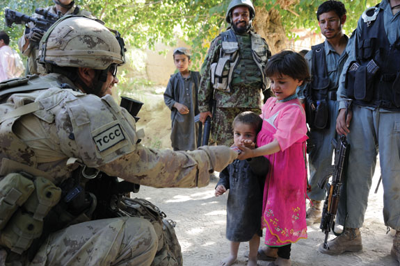 A soldier hands food to Afghan children