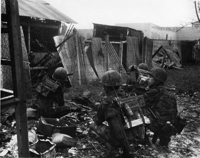 Gia Dinh, Vietnam. Un commandant de compagnie de l’ARVN, accompagné d’un conseiller américain (à droite), livre un assaut sur un entrepôt de riz occupé par des soldats nord-vietnamiens.