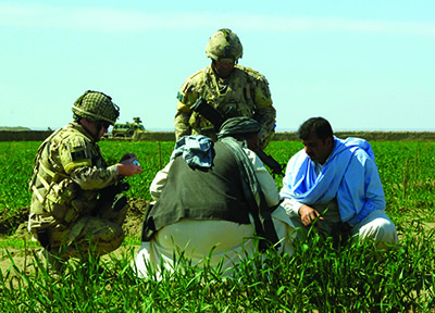 Reservists Captain Richard Nolan (left) and Captain Clayton Ereaut, both originally from Newfoundland, listen to the owner of a pomegranate tree nursery in Afghanistan as Civil-Military Cooperation team members of the Kandahar Provincial Reconstruction Team, 1 April 2007.