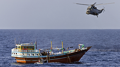 HMCS Charlottetown’s boarding party conducts a search of a dhow boat while a Sea King helicopter provides cover in the Gulf of Aden while participating in Operation Artemis during May 2012.