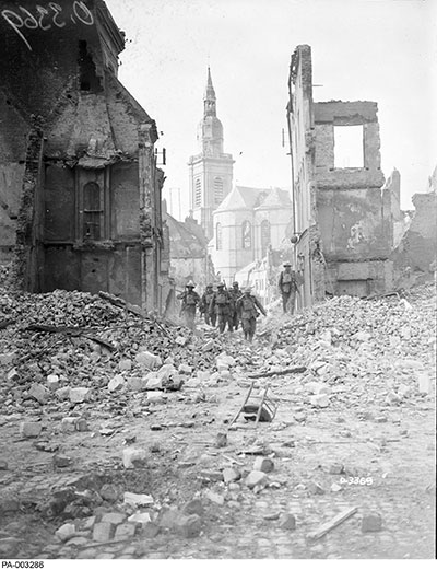 Des Canadiens marchent dans les ruines de Cambrai en octobre 1918.