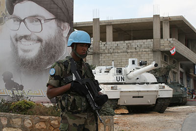 A French UN peacekeeper stands guard in front of a poster of Hezbollah leader Sayyed Hassan Nasrallah at a checkpoint in Adaisy village near the border with Israel in south Lebanon.