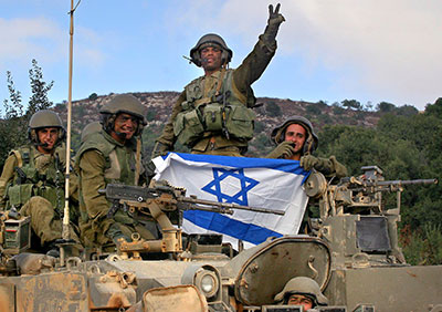 Israeli soldiers hold their national flag after returning from Lebanon, near the Israeli-Lebanese border, 14 August 2006.