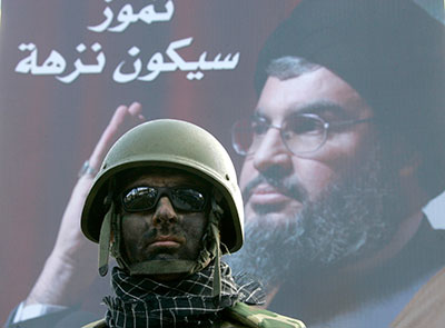 Hezbollah member stands in front of a poster of his leader, Sayyed Hassan Nasrallah, during a procession held to celebrate Ashura in south Lebanon, 10 January 2009. 
