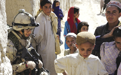 Afghan children surround Corporal Marie-Anne Hardy as she takes a break during an early morning operation to conduct cordoned searches of fields and compounds, 4 June 2011.