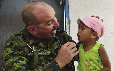 Master Corporal Stephane Fortin, medical technician for the 2nd Canadian Field Ambulance, Petawawa, and member of the Canadian Armed Forces Disaster Assistance Response Team, examines the tonsils of a local child during Operation Renaissance, in Sara, Philippines, 21 November 2013.