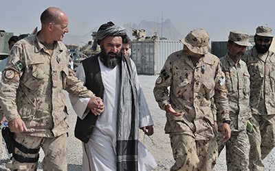 Le brigadier-gnral Dean Milner et un leader de district afghan marchent cte  cte avant le dbut dun shura pour discuter denjeux de gouvernance et de scurit.