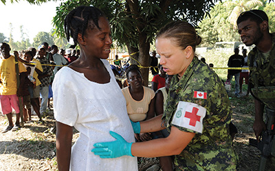 A female medic provides medical care to a pregnant Haitian woman.