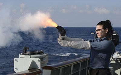 A female reserve force Naval Communicator on board HMCS ‘Winnipeg’ fires a warning flare during a force protection exercise.