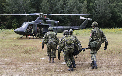Canadian Army reservists from 4th Canadian Division medical units advance to load a simulated casualty onto a CH-146 ‘Griffon’ during Exercise Stalwart Guardian.
