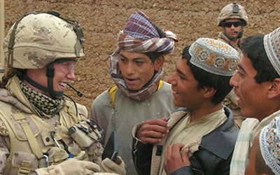 A female Reservist member of Civil-Military Cooperation from the Kandahar Provincial Reconstruction Team speaks with local Afghan youths during a patrol.