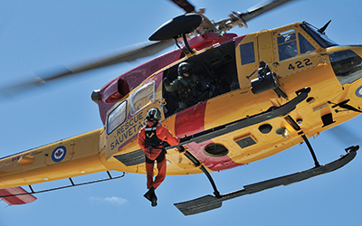 A SAR technician being hoisted aboard a SAR CH-146 Griffon helicopter.