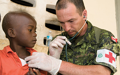 A member of the Mobile Medical Team/Disaster Assistance Response Team examines a little boy in Haiti during Operation Hestia.