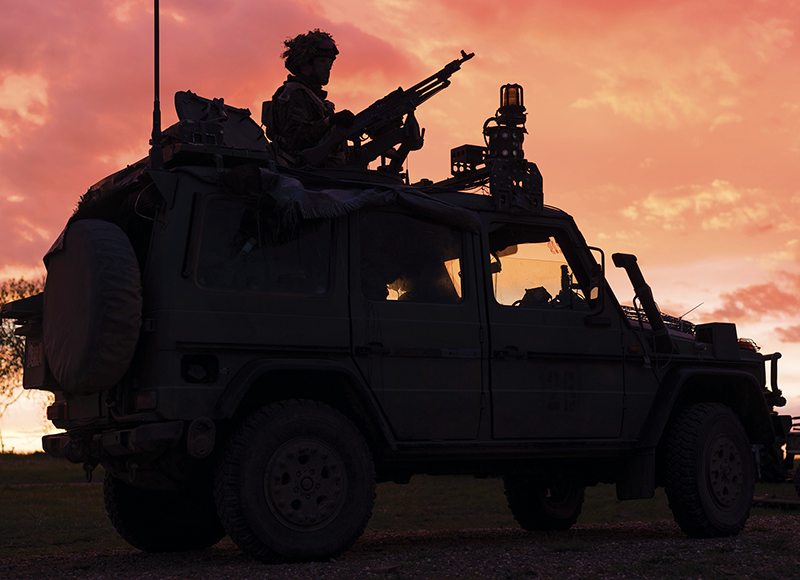 Soldier on Light Utility Vehicle at dusk.