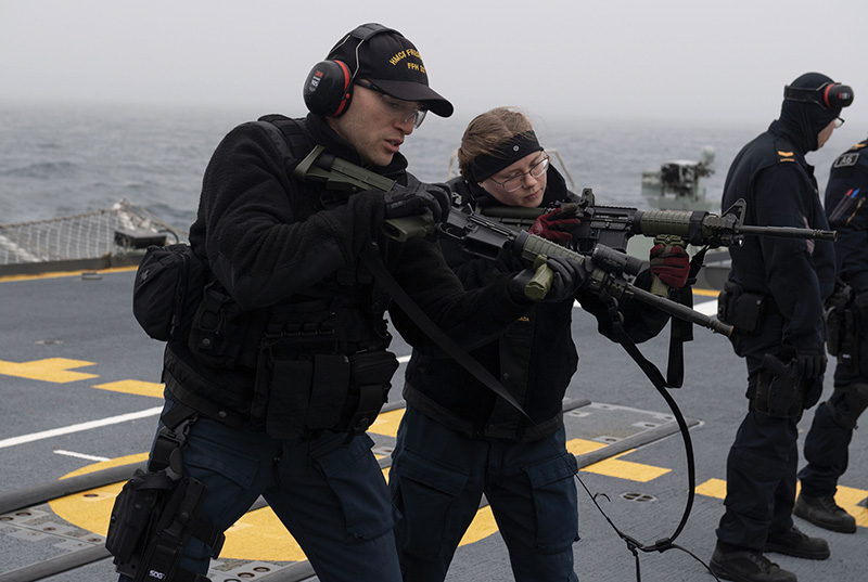An RCN lieutenant mentors an able seaman from ship’s boarding party with respect to shooting.